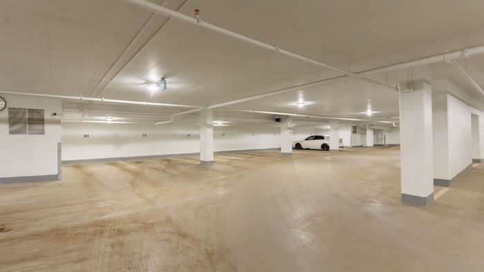 A well lit underground parking garage with open parking spaces.