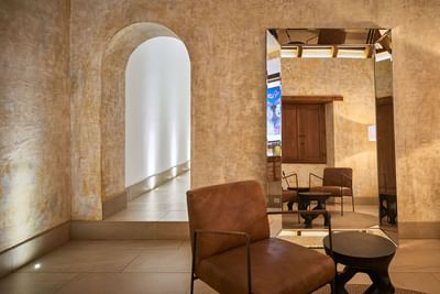 Stylish seating area with a mirror, armchair, and an arched hallway at Singular Signature Residences