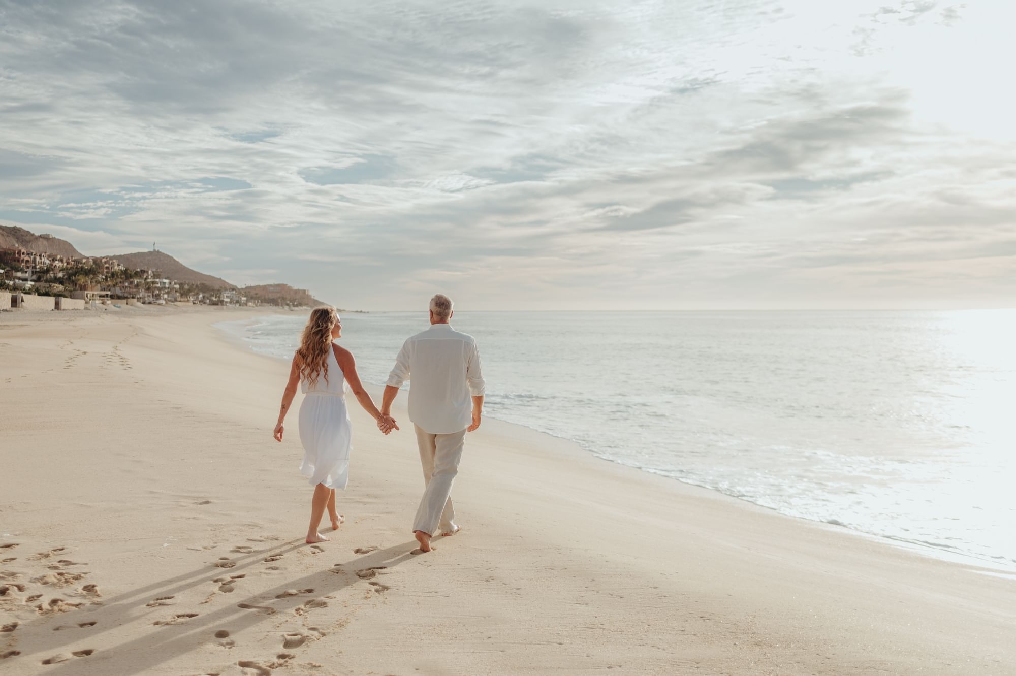 Couple walking hand-in-hand along a serene beach at Marquis Los Cabos