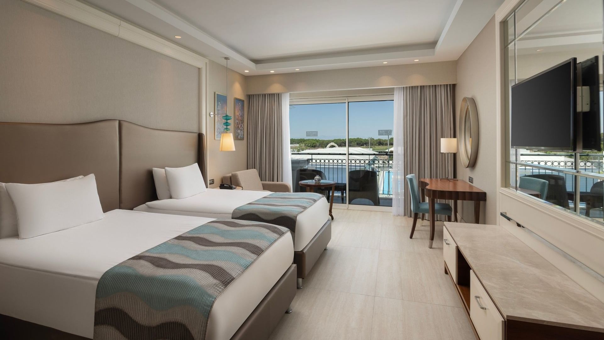 İki ayrı yatak, balkon ve modern mobilyalarla döşenmiş Family Suite Garden odası, Titanic Deluxe Golf Belek'te