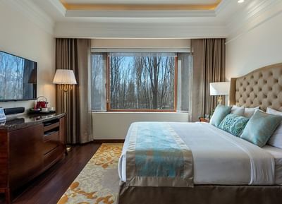TV stand facing the king bed with a cushioned headboard in Royal Family Suite at The Indus Valley Leh, Hotel Stay in Leh