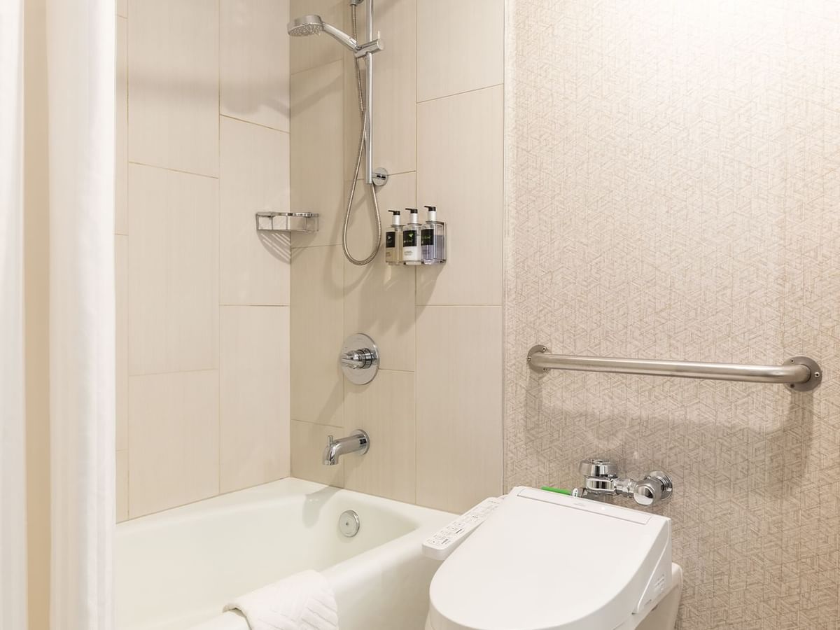 A modern accessible bathroom with a bathtub, toilet, and grab bar.