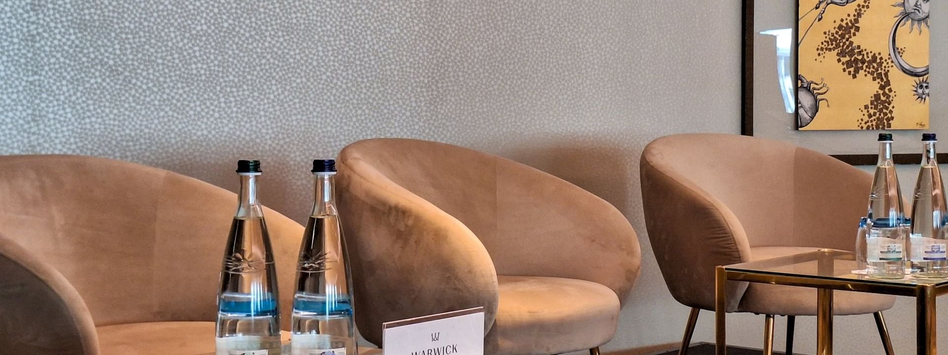 Tan armchairs surrounding an oval table under a large screen and glass wall in Mont-Blanc + Jura at Warwick Geneva