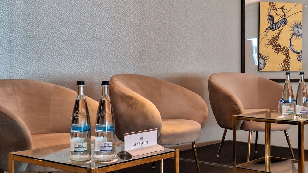 Tan armchairs surrounding an oval table under a large screen and glass wall in Mont-Blanc + Jura at Warwick Geneva