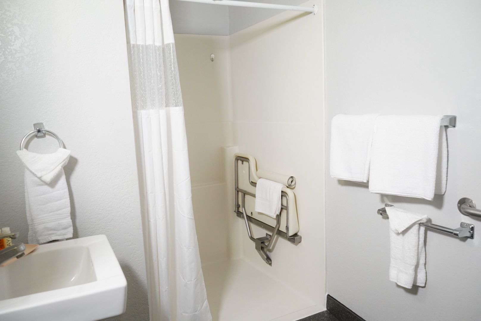 A standard hotel bathroom with a shower, sink, and towels