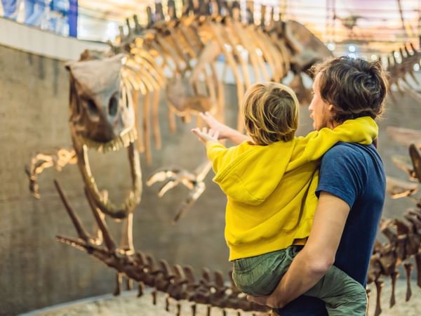 A father and a son looking at a skeleton of a dinosaur