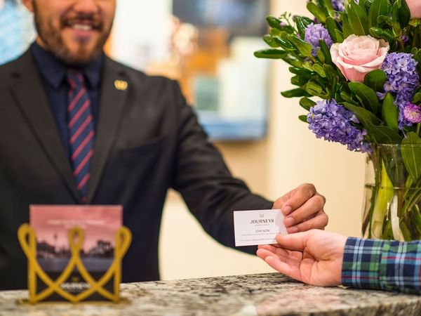 Receptionist holding a hotel card at Warwick Seattle
