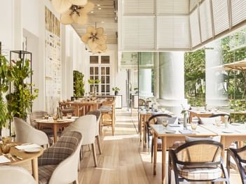 Opera featuring wooden tables, elegant chairs, and lush greenery, with large windows at Park Hyatt Saigon