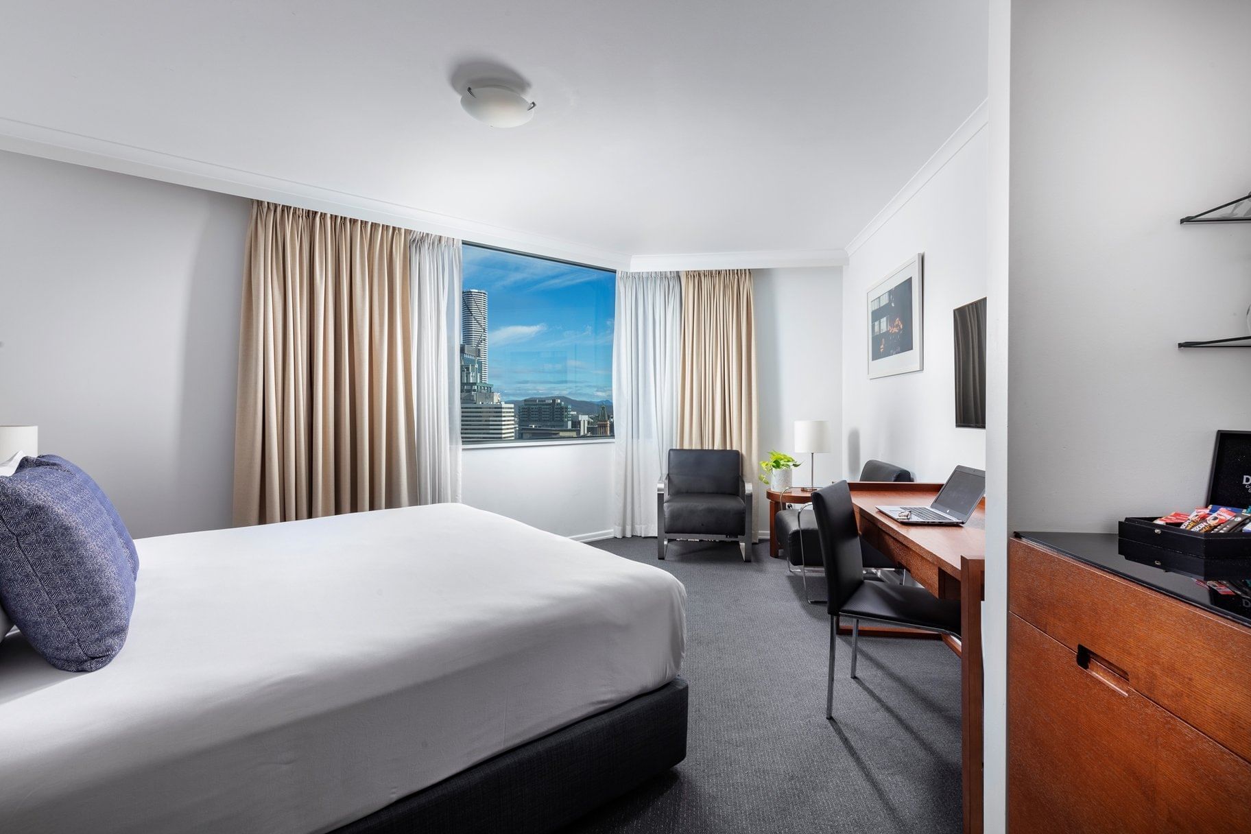 Premium Studio Room featuring a city skyline, desk area, seating chair, and clean white bedding at The Sebel Brisbane