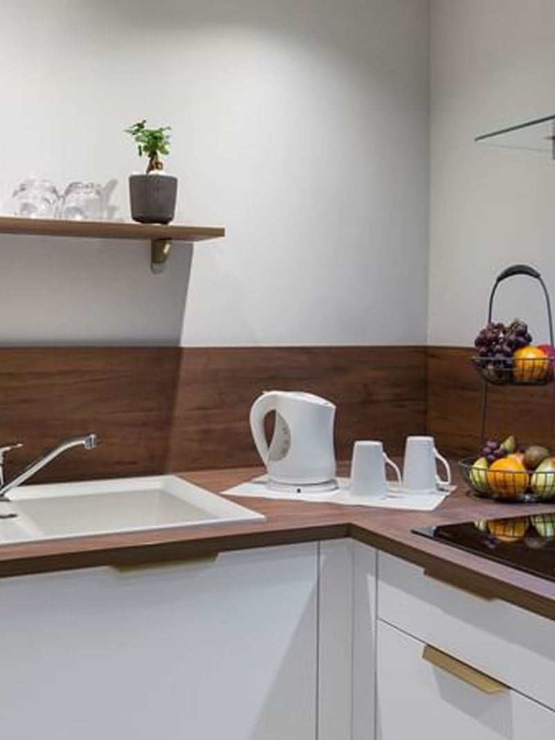 Modern kitchen corner with white cabinets and wooden countertops in the Premium Suite at Warwick Reine Astrid - Lyon