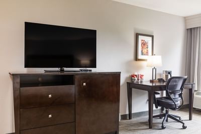 Premium King Room workspace with a dark wood dresser, flat-screen TV, desk chair, and a lamp at Branson Hillside Hotel