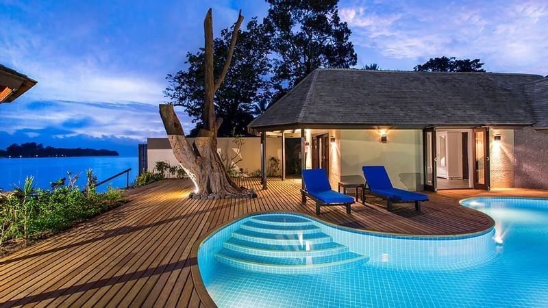 Efate Pool Villa featuring curved infinity pool and wooden deck with blue loungers at twilight at warwick le lagon-vanuatu 