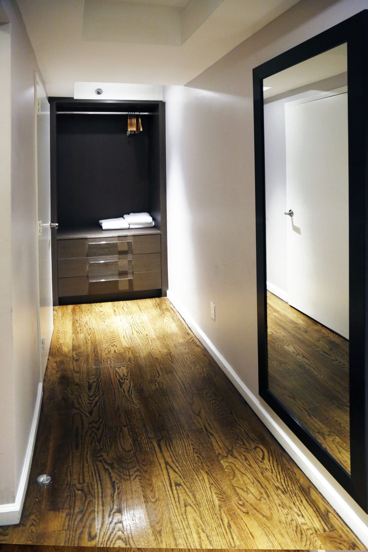 A closet with a large mirror, drawers, and a closet organizer system.