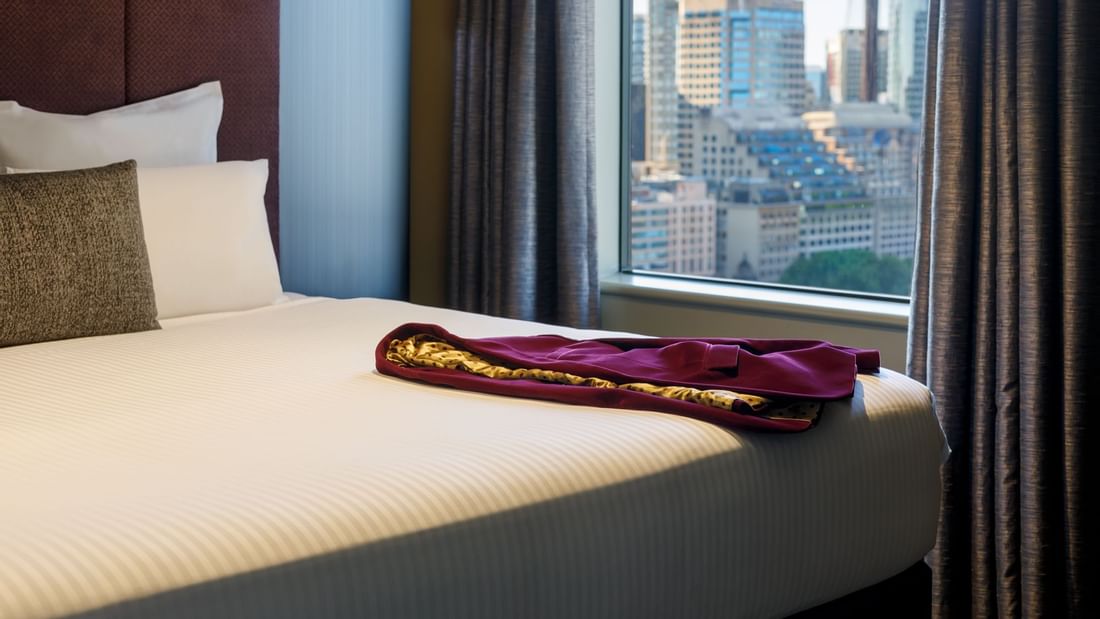 Dress on a cozy bed in a room with a city view at Pullman Sydney Hyde Park