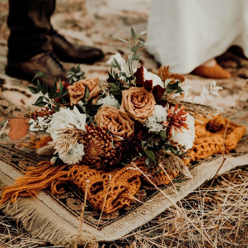 Close up of Autumn-hued bouquet and bride and groom's footwear at The Stonebreaker Hotel