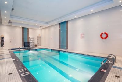 Indoor pool with adjacent hot tub, metal handrails and tiled floor at Winnipeg Airport Hotels