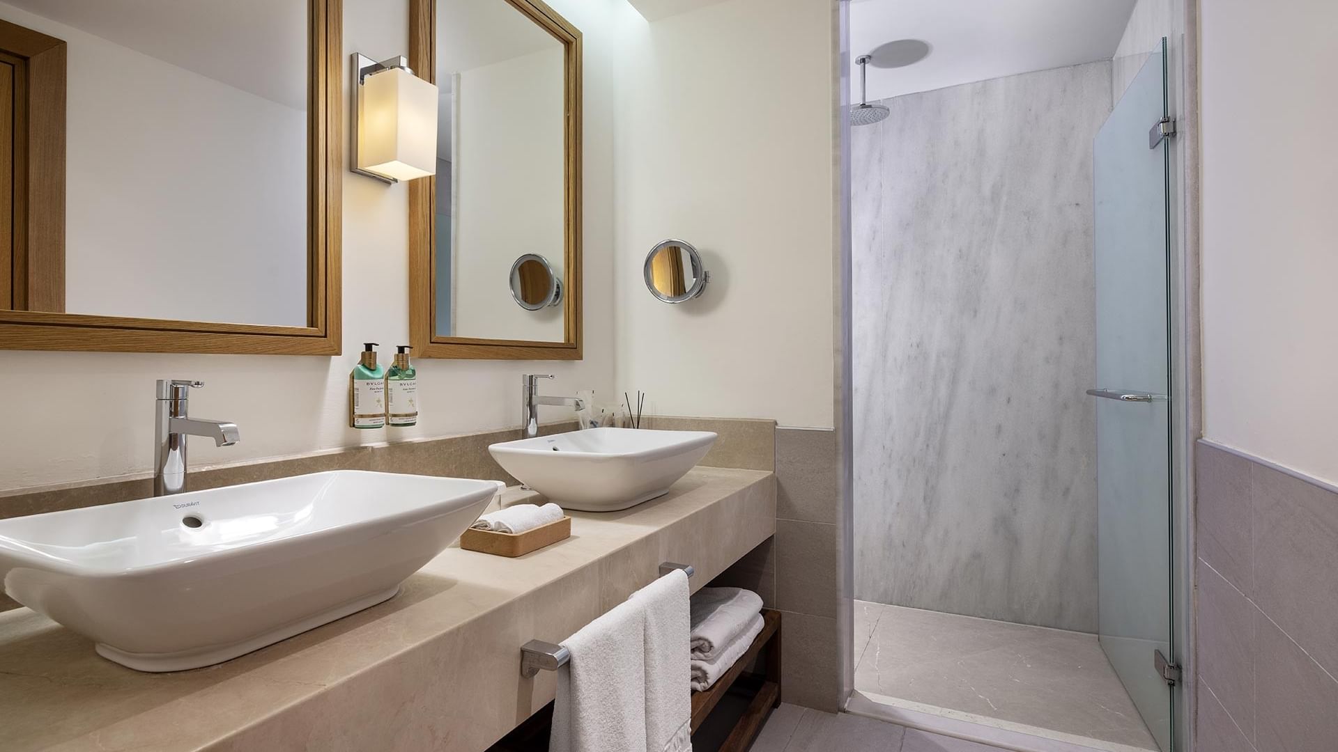 Double sinks with faucets and towels, two mirrors, and a shower in Swim-up Superior Room's bathroom.