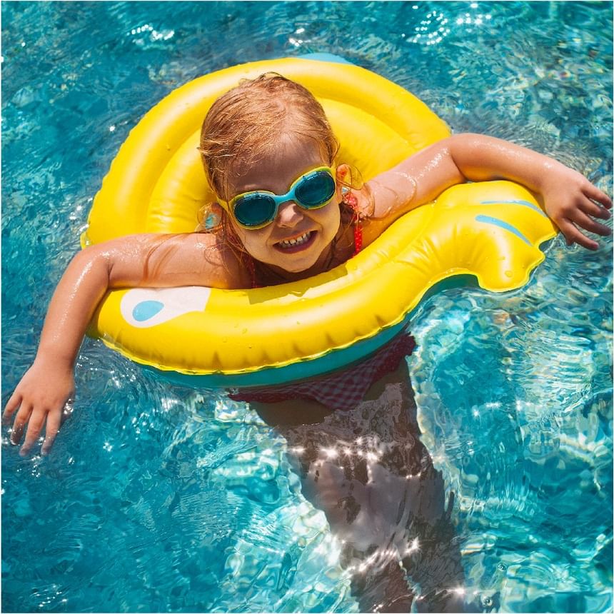 Niño sonriente con gafas azules descansa en un flotador amarillo dentro de la piscina de Megapolis Hotel Panama