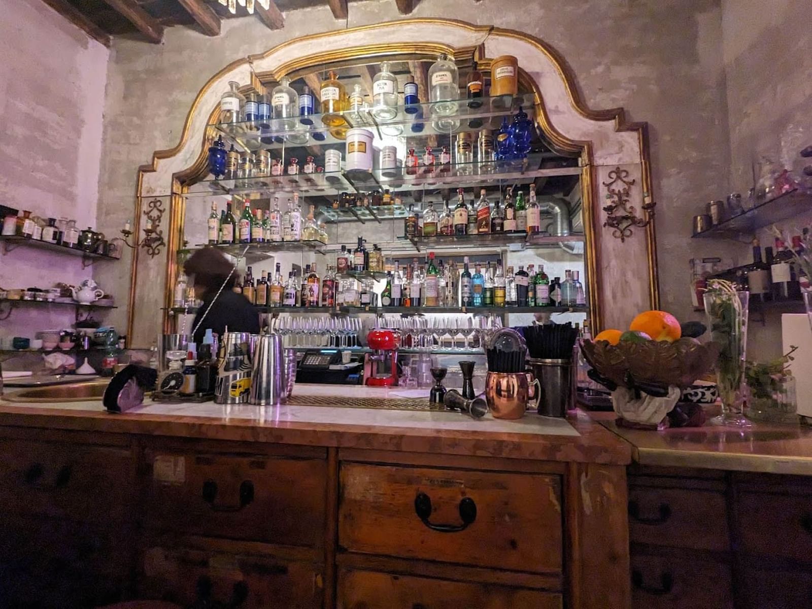 Sacripante Art Gallery featuring a wooden counter, shelves stacked with various liquor bottles near The Glam Hotel