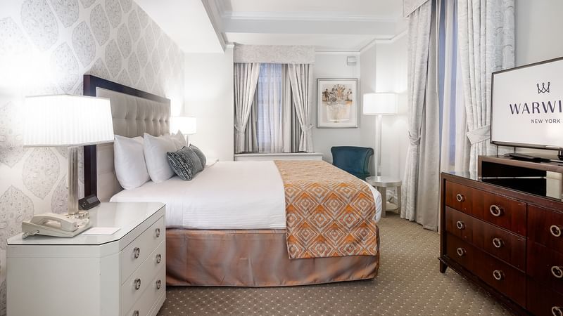 Comfy bed with side tables and TV in Premier Suite at Warwick New York