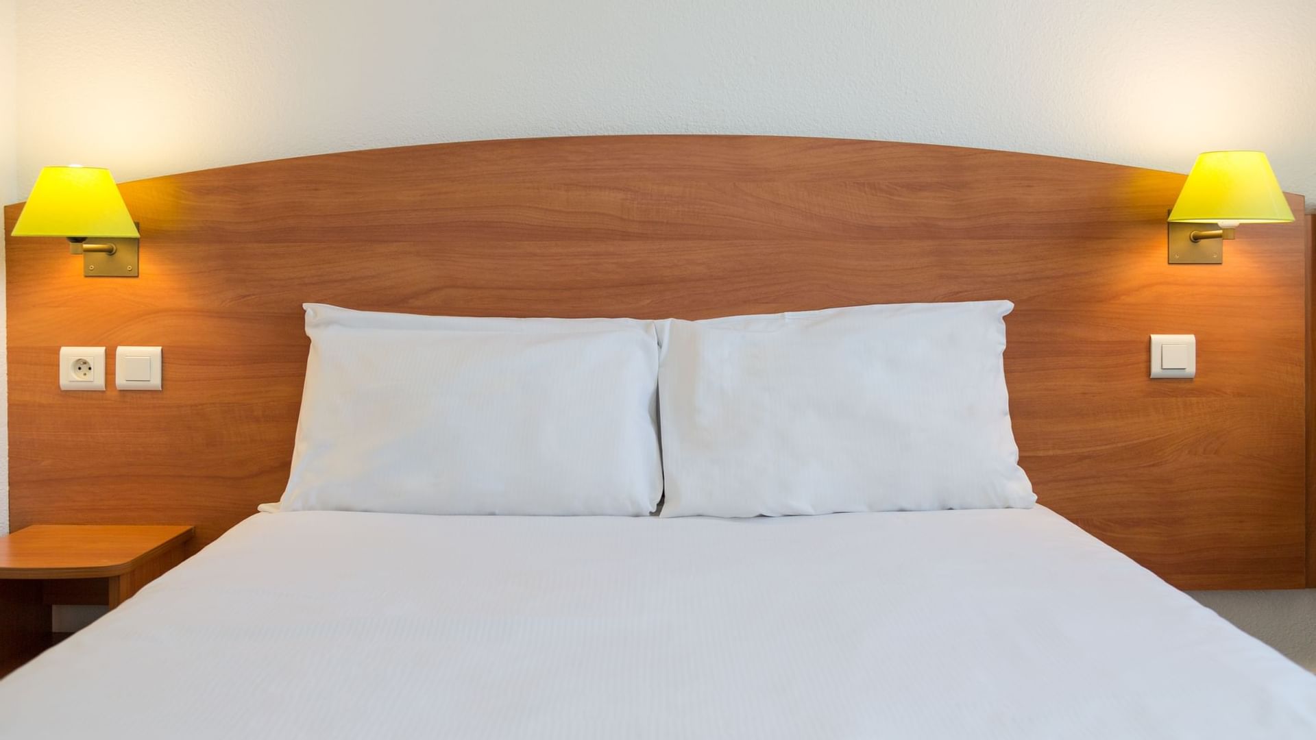 Closeup of a double bed with white bedding at Originals Hotels
