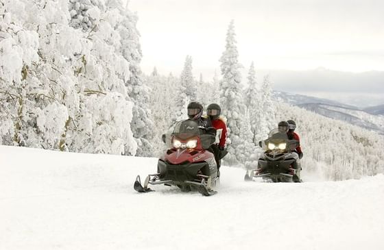 Two couples snowboarding through snowy mountains.