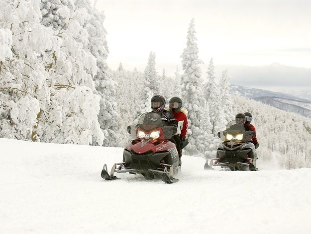 Four people snowmobiling near Topnotch Stowe Resort