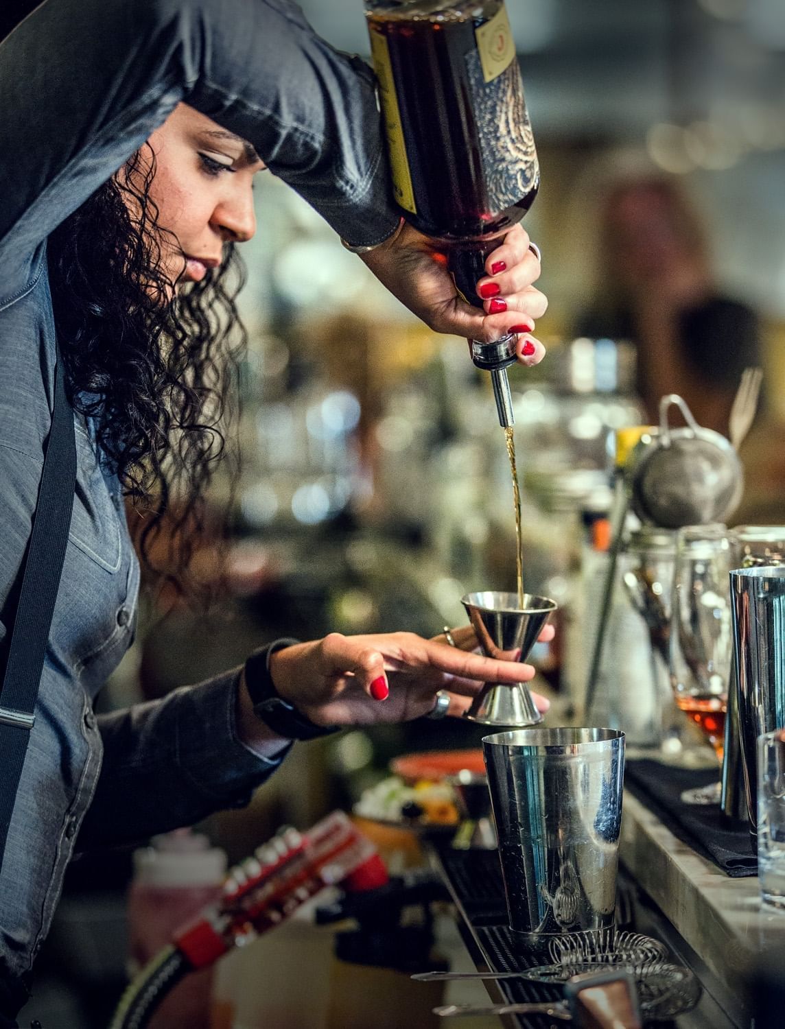 Lorem ipsum Woman bartender preparing a mix drink behind the bar.