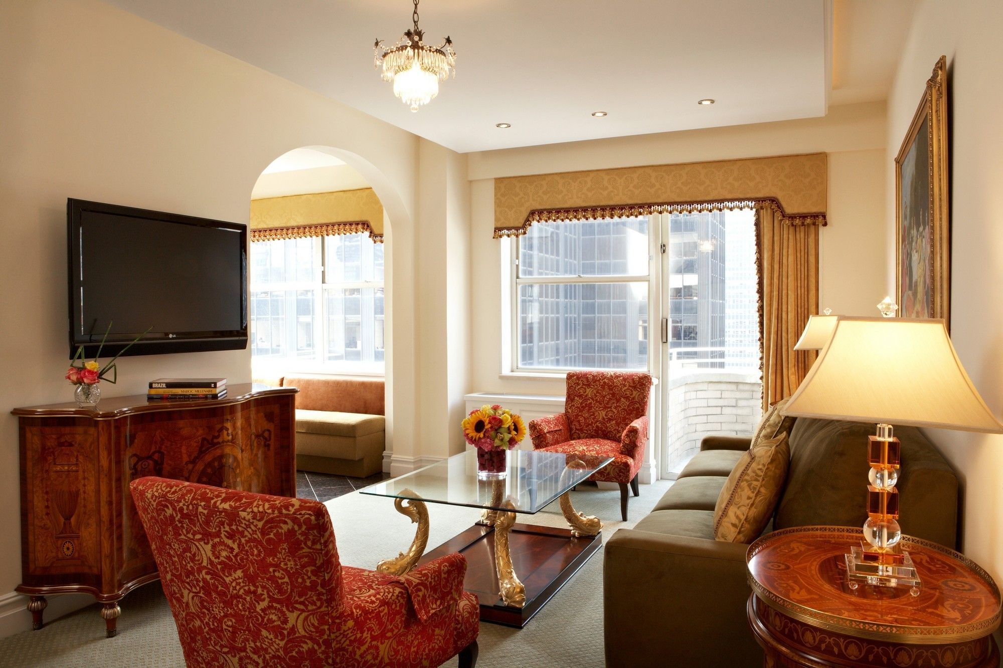 A luxurious living room with a sofa, armchairs, coffee table, and TV.