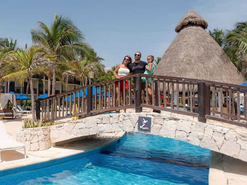 Family crossing a bridge over the pool at The Reef Coco Beach