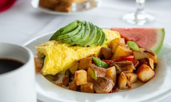 Breakfast plate with an omelete, potatoes and a watermelon slice