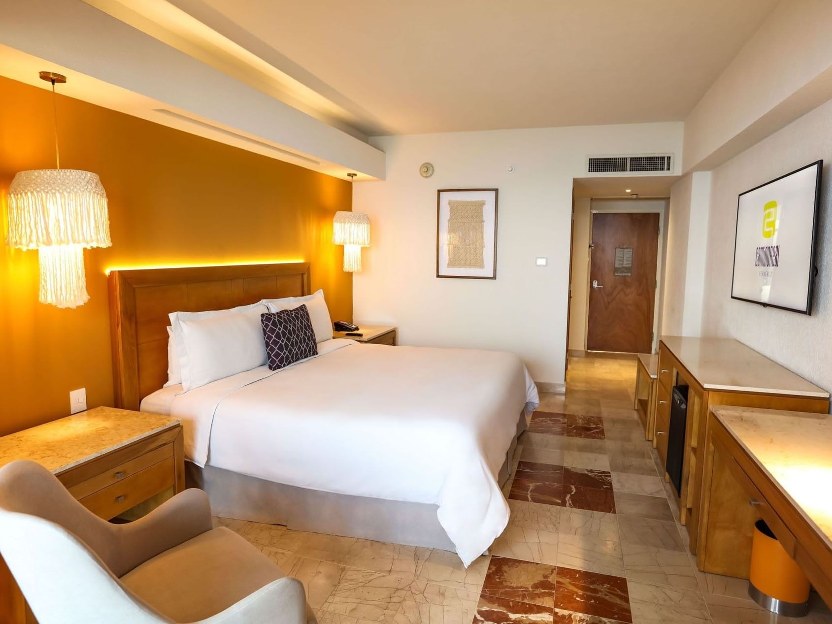 Full view of a King Camino Real Club with a desk area, lounge chair, and warm decorative lighting at Camino Real Veracruz