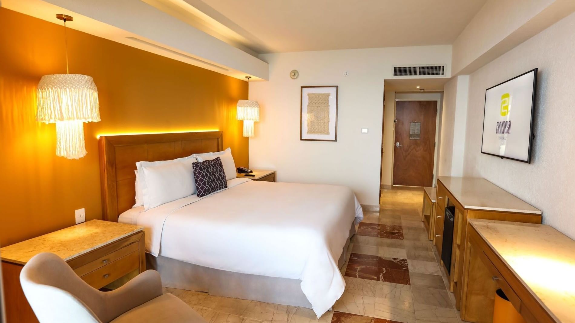 Full view of a King Camino Real Club with a desk area, lounge chair, and warm decorative lighting at Camino Real Veracruz