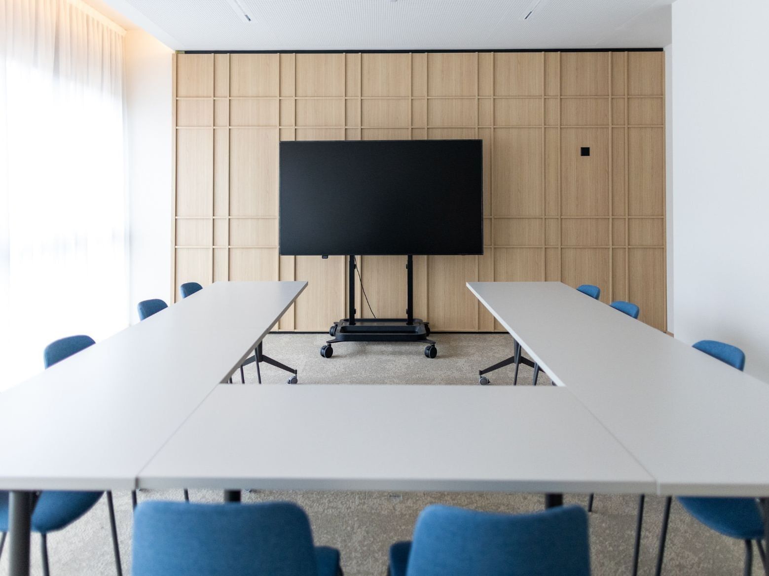 U-shaped conference table setup at Hotel des Innovations with a large screen and modern wood paneled wall