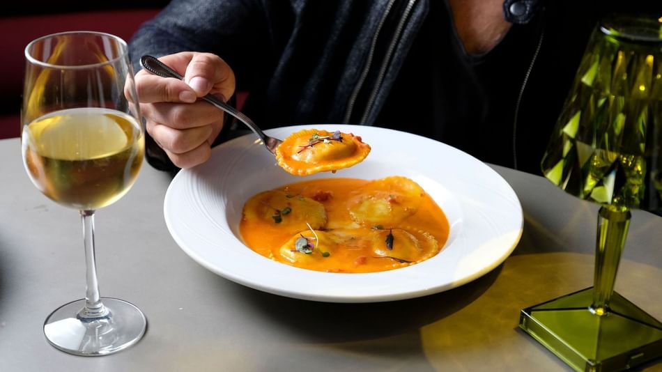 women with a bowl of ravioli pasta and glass of wine