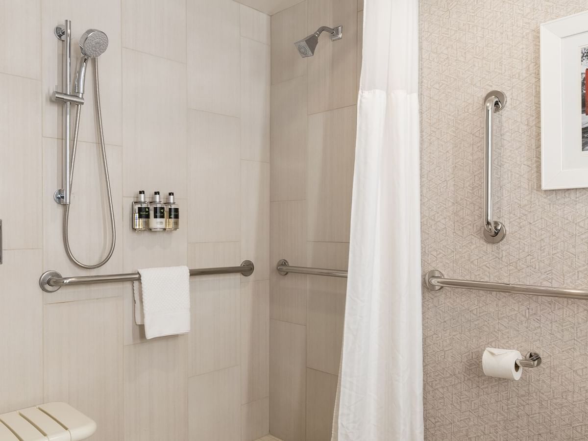 Accessible roll-in shower with grab bars, towel, and shampoos.