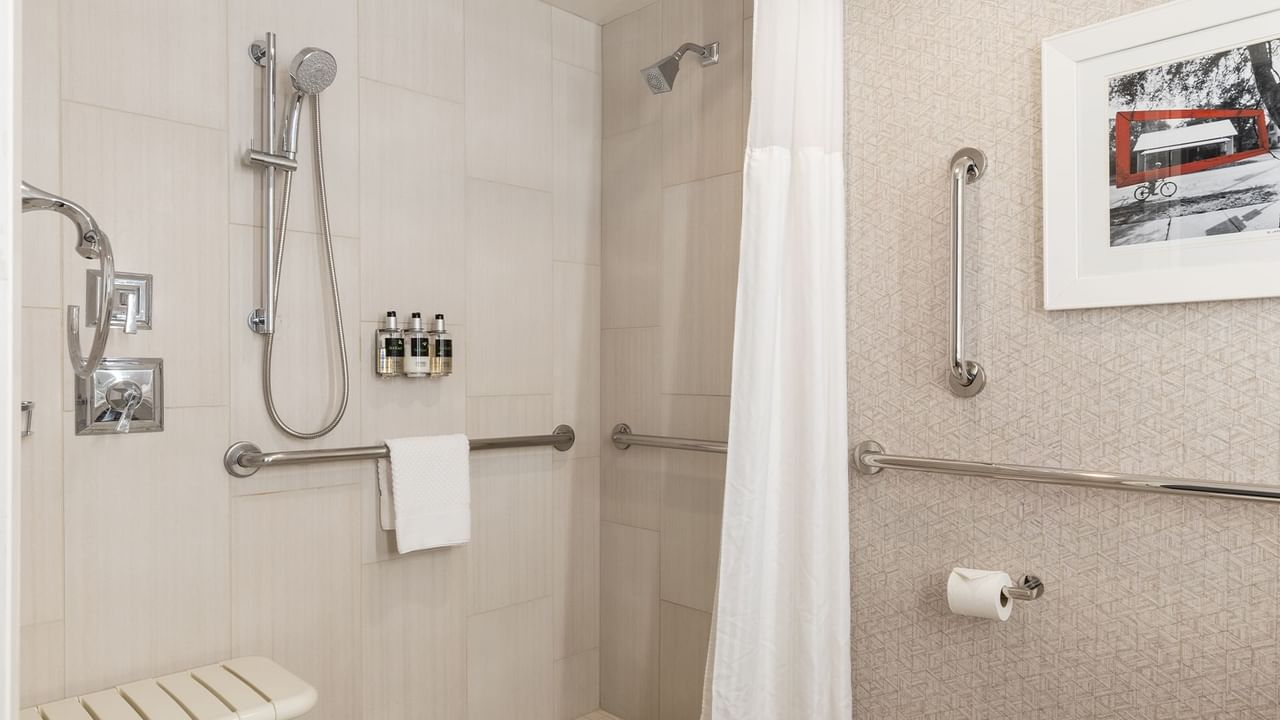Accessible roll-in shower with grab bars, towel, and shampoos.