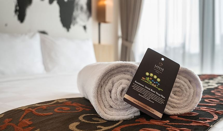 Close-up of rolled towels on the bed in King Bed Deluxe Room at LK Cikarang Hotel & Residences