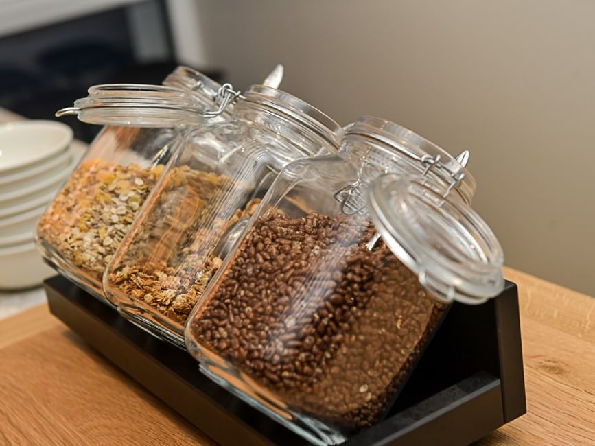 Trois bocaux de céréales sur plateau en bois dans Hôtel Rivella.