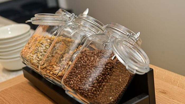 Trois bocaux de céréales sur plateau en bois dans Hôtel Rivella.