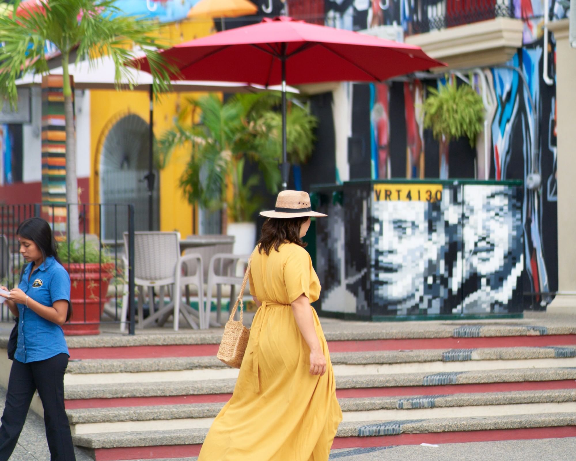 Woman walking near colorful street art and umbrellas on the Malecón in downtown Puerto Vallarta