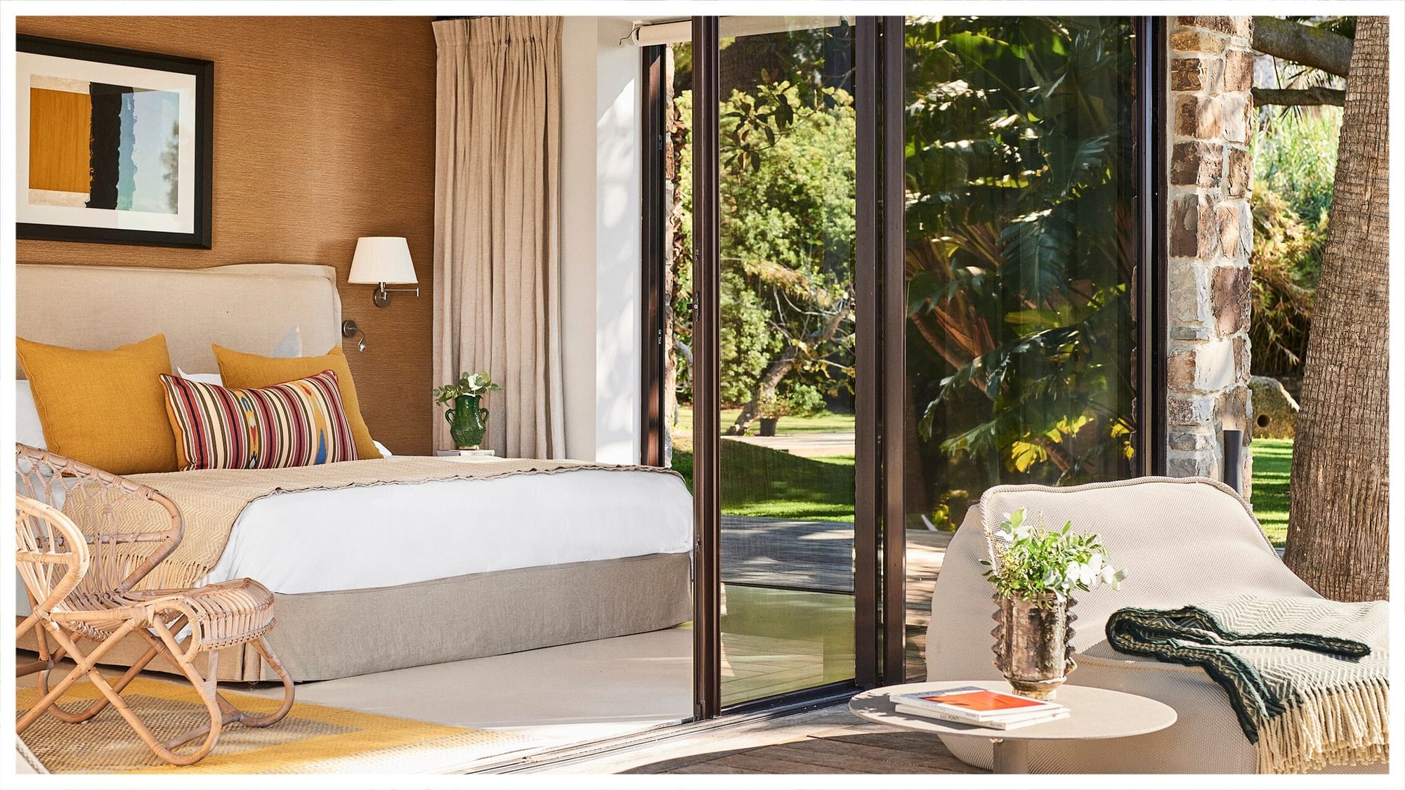 Sunlit bedroom at Marbella Club villa with a large bed, yellow accents, and garden patio views