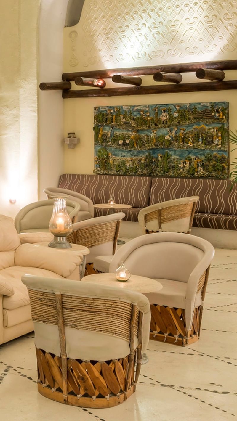 Bar Las Cúpulas Lounge chairs by a wooden railing under a leafy canopy, surrounding an ocean view at Quinta Real Huatulco