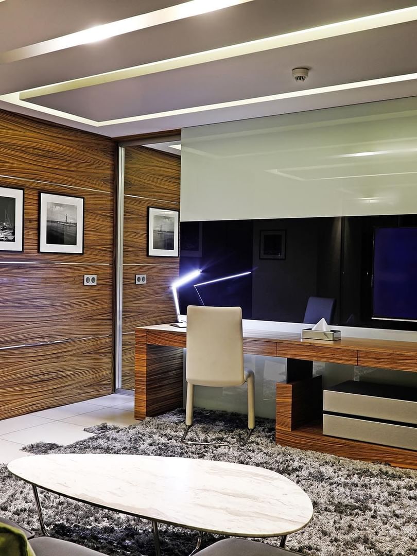 Wooden desk by a TV under a recessed ceiling near a marble coffee table in Executive Suite at Warwick Stone 55 - Beirut