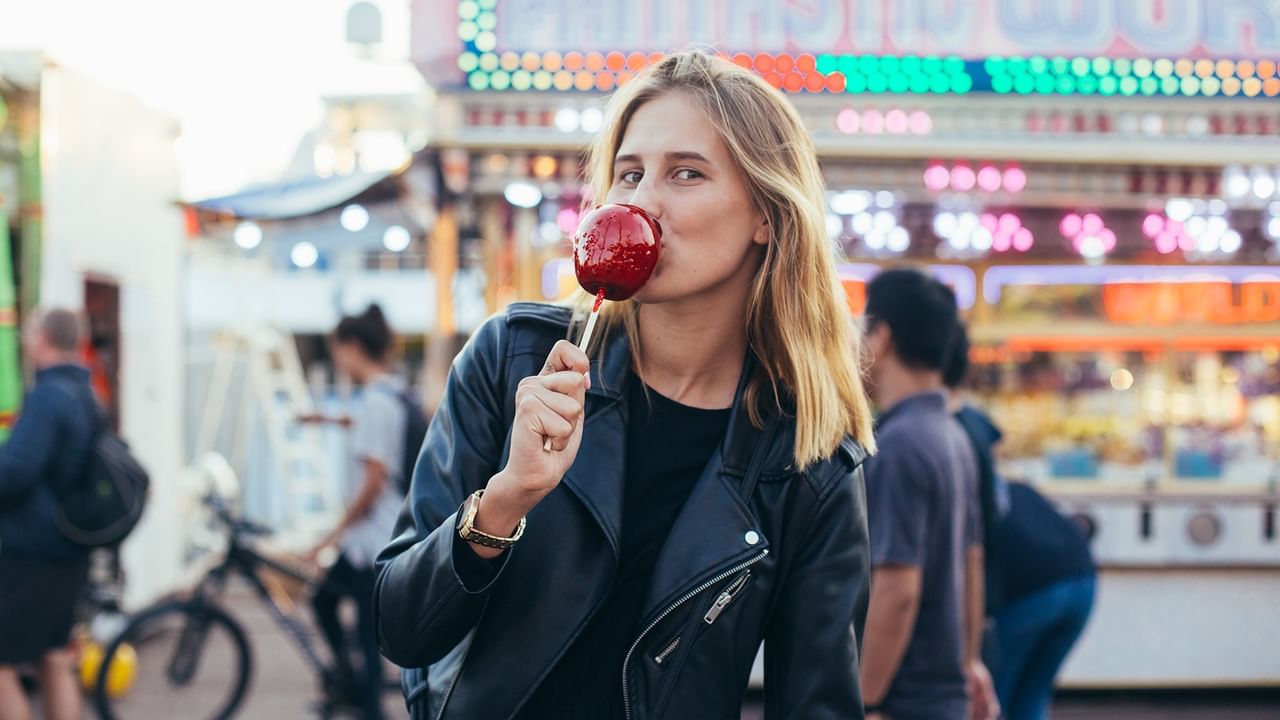 Blonde woman in leather jacket enjoying an apple lollipop at Whitecourt Trade Fair.