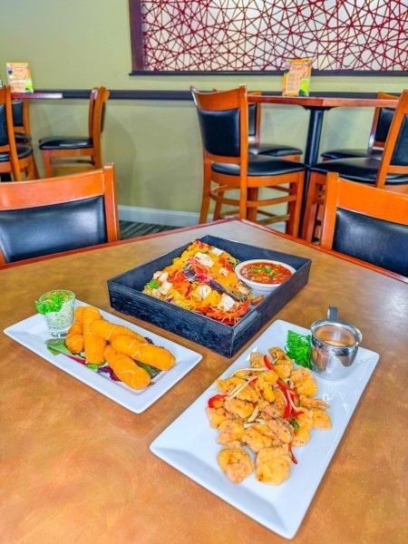 A spread of delicious meals sitting on a table at Comfort Zone Bar & Grille at Rosen Inn Lake Buena Vista, a family-friendly hotel in Orlando.