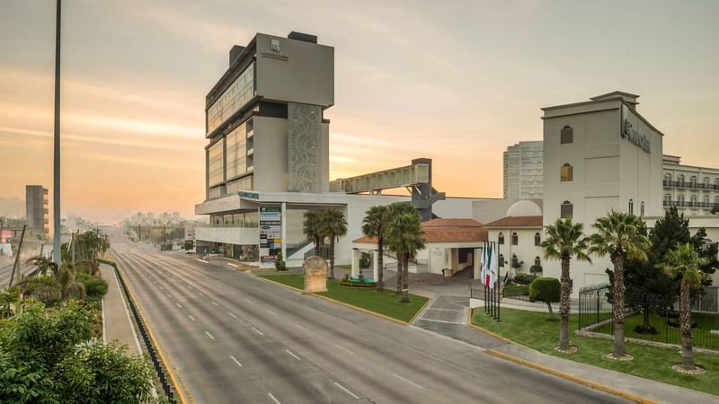 Wide street view of Camino Real Puebla Angelopolis, highlighting the hotel's unique and towering design