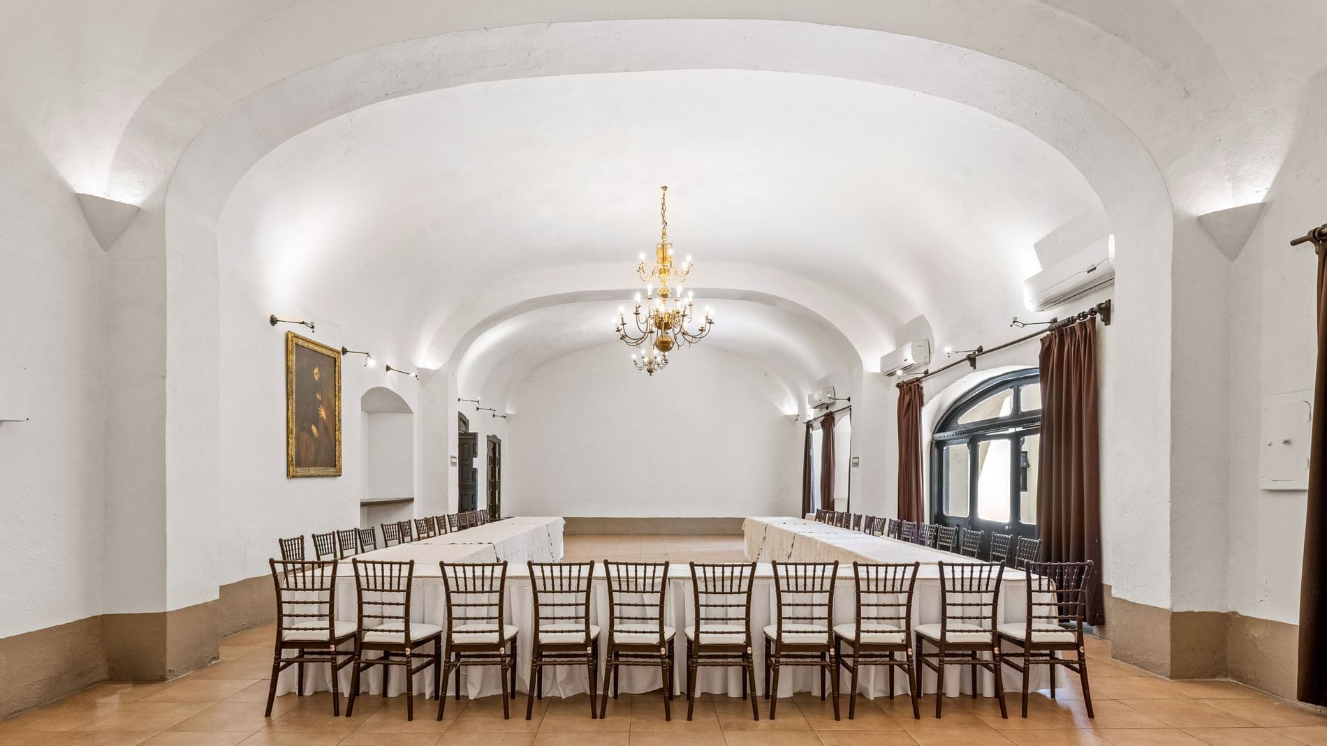 Large U-shaped conference table setup in a white vaulted room with a gold chandelier in Cholula at Quinta Real Puebla