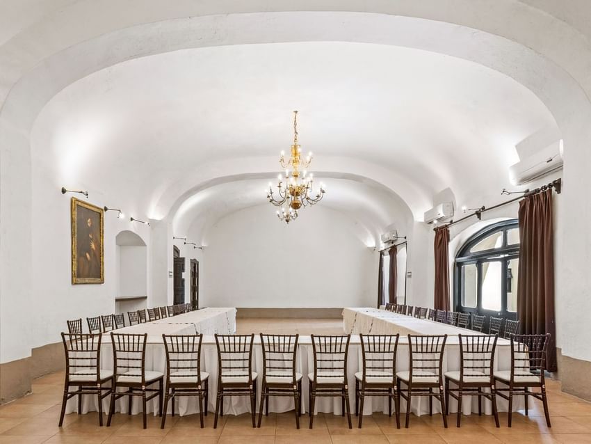 Large U-shaped conference table setup in a white vaulted room with a gold chandelier in Cholula at Quinta Real Puebla