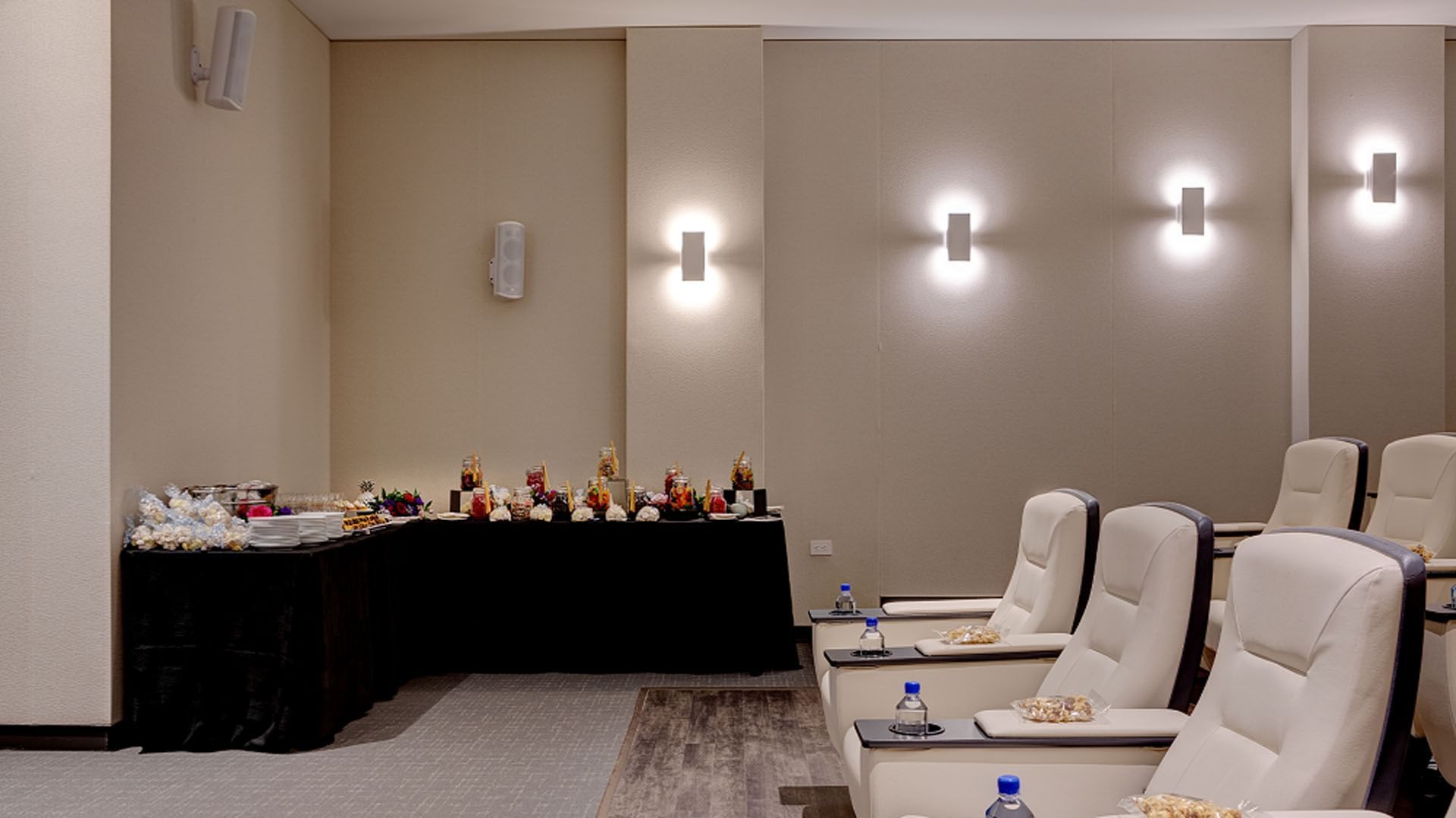Private cinema screening room with plush reclining chairs facing a snack table and wall sconces at Hotel X Toronto